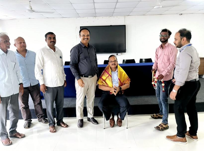 Dr Hegde seated wearing a ceremonial shawl among colleagues