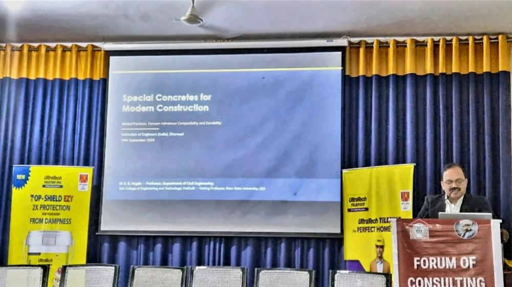 Dr Hegde speaking at a lectern beside a projected slide titled Special Concretes for Modern Construction