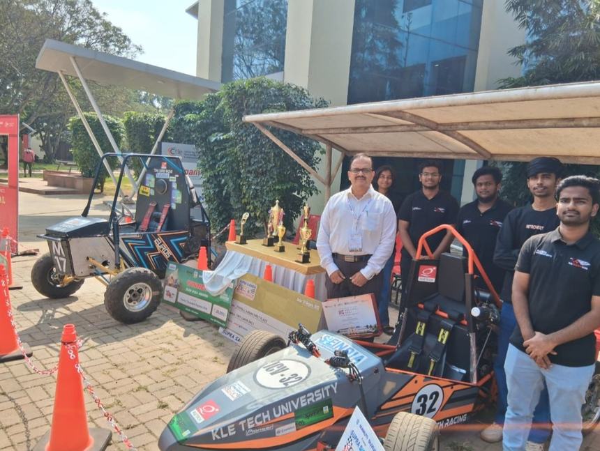 Dr Hegde with engineering students beside their racing cars and trophies